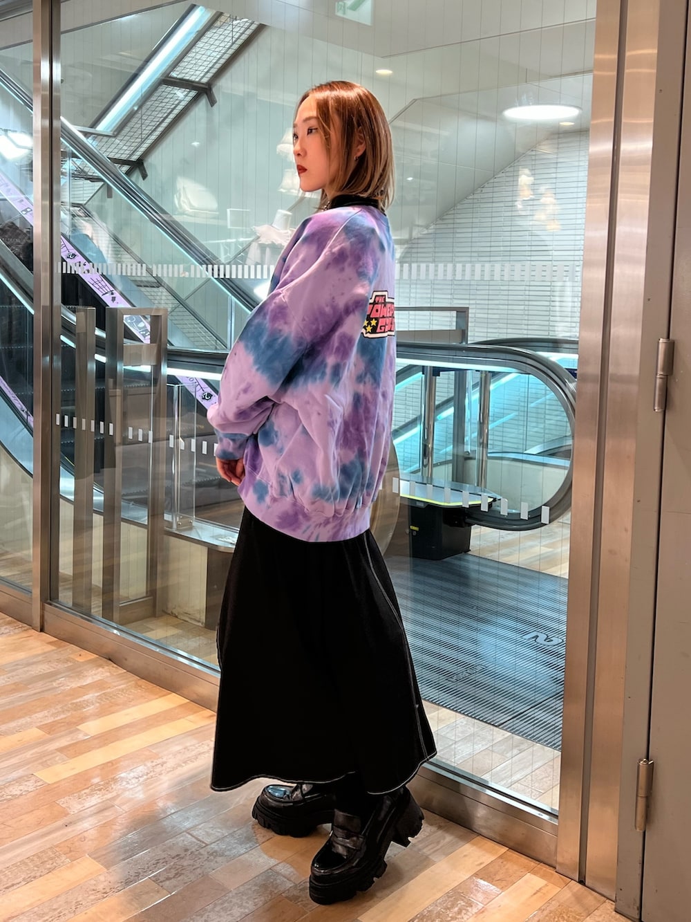 パープル系のスウェット、ブラック系のワンピース、ブラック系のローファーを着用したレディースの春コーディネートの2枚目の写真