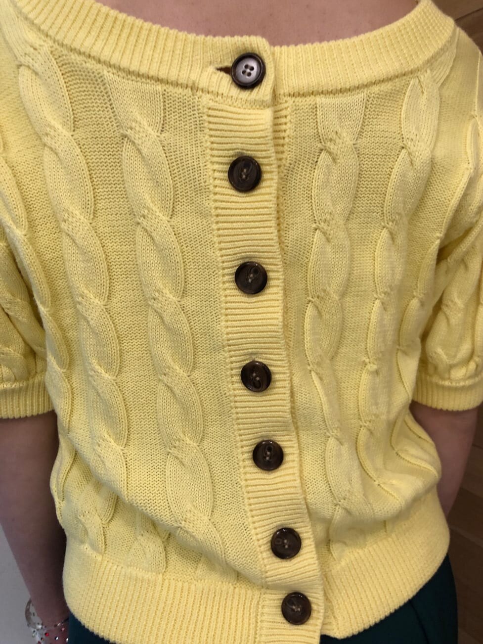 グリーン系のスラックス、イエロー系のニット/セーター、シルバー系のネックレスを着用したレディースの冬コーディネートの6枚目の写真