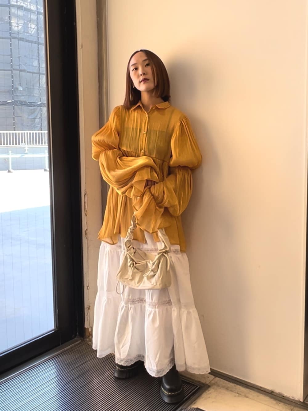 オレンジ系のシャツ/ブラウス、ホワイト系のスカート、ホワイト系のショルダーバッグを着用したレディースの春コーディネートの2枚目の写真