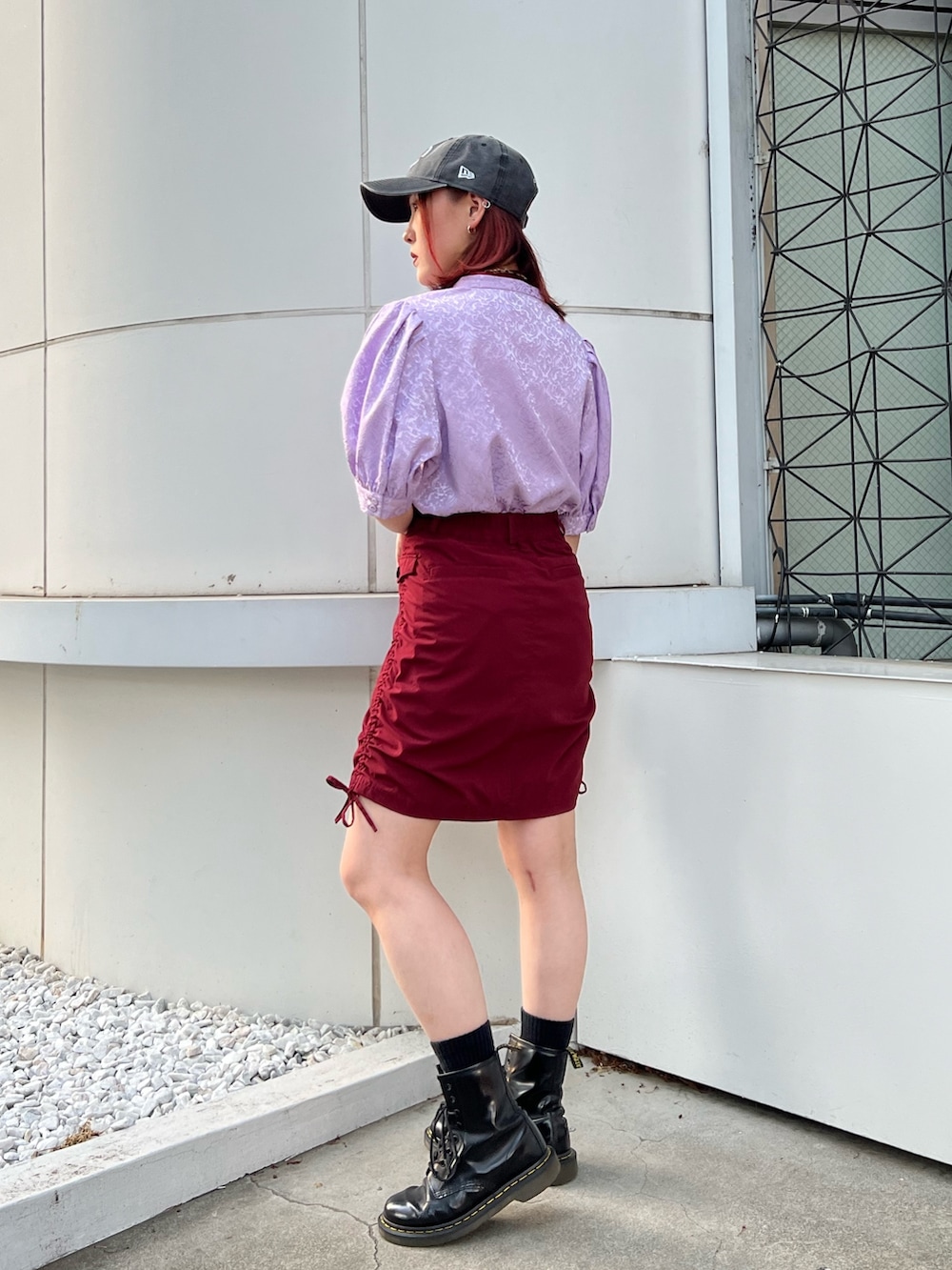 パープル系のシャツ/ブラウス、レッド系のスカート、ブラック系のキャップを着用したレディースの春コーディネートの4枚目の写真