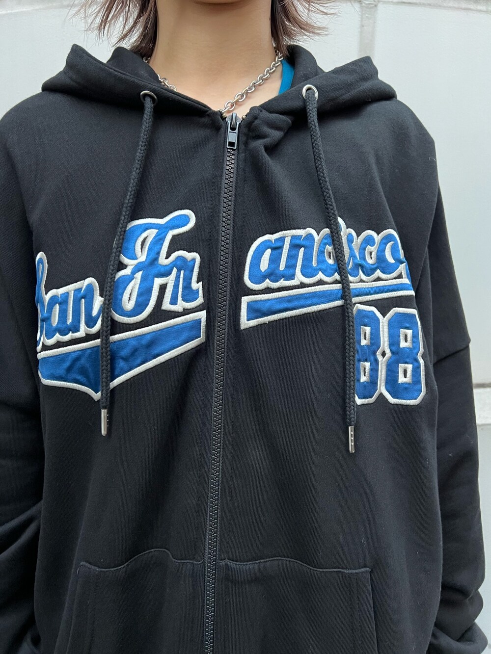 ブルー系のスカート、ブラック系のパーカー、ブルー系のタンクトップを着用したレディースの春コーディネートの7枚目の写真