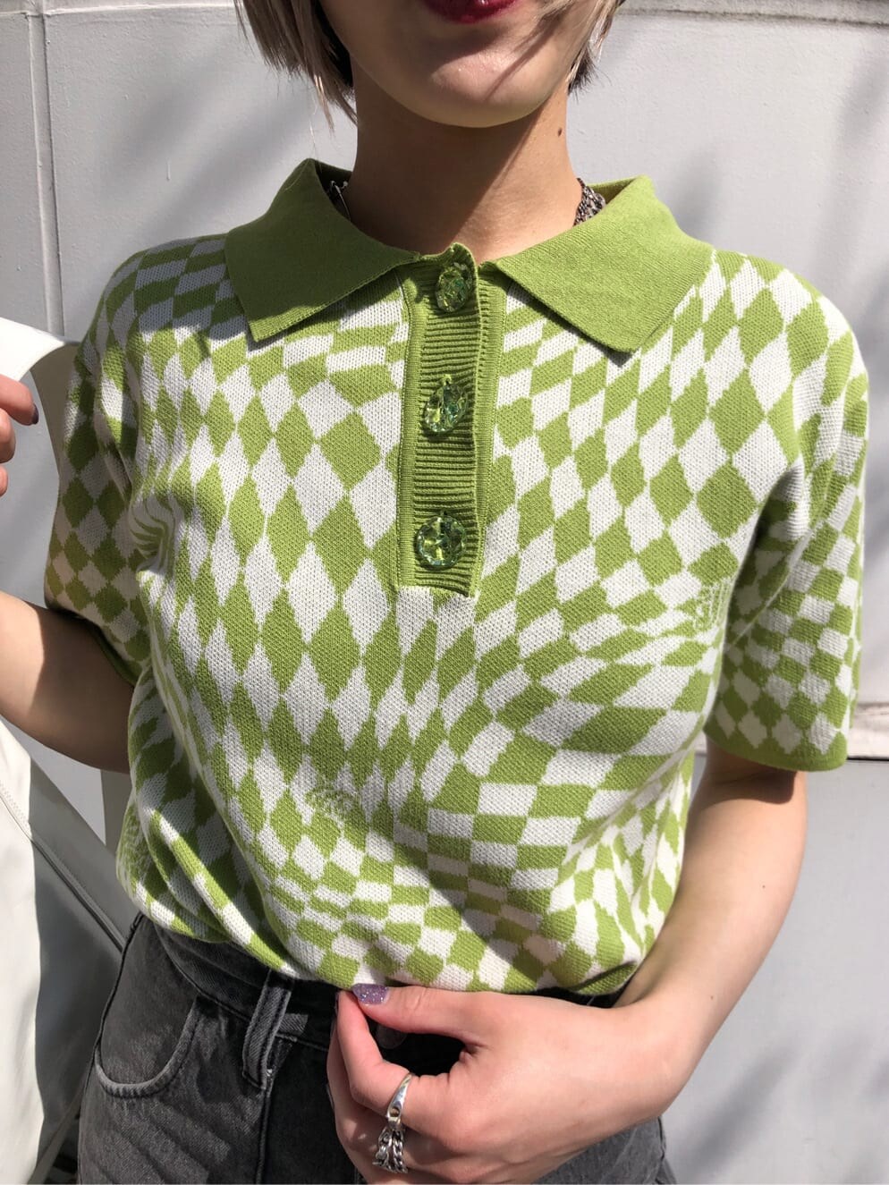 グリーン系のニット/セーター、ブラック系のデニムパンツ、ホワイト系のハンドバッグを着用したレディースの夏コーディネートの5枚目の写真