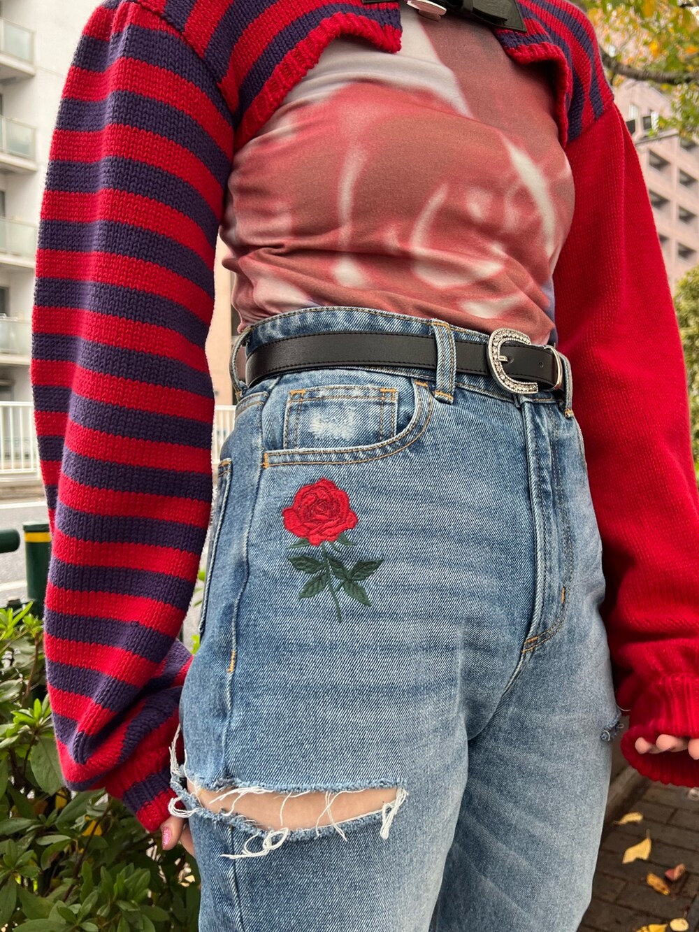 レッド系のニット/セーター、パープル系のTシャツ/カットソー、ブルー系のデニムパンツを着用したレディースの冬コーディネートの7枚目の写真