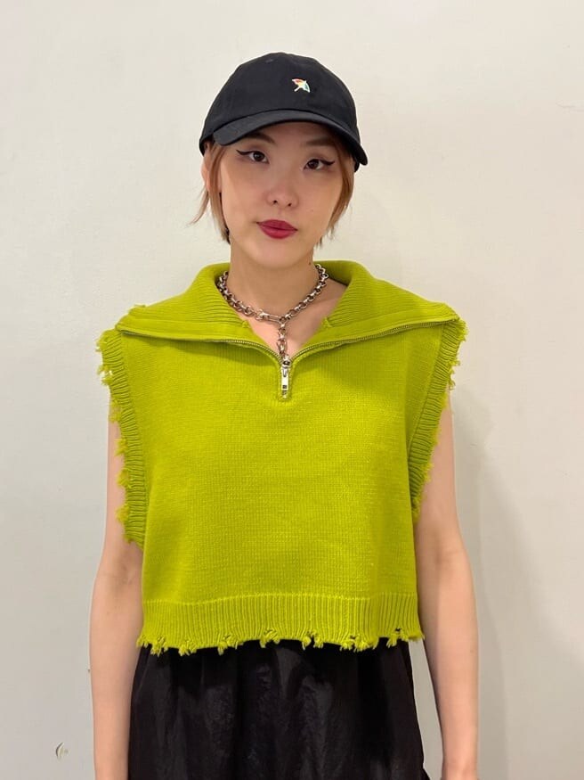 ホワイト系のローファー、グリーン系のベスト、ブラック系のジャンパースカートを着用したレディースの秋コーディネートの7枚目の写真