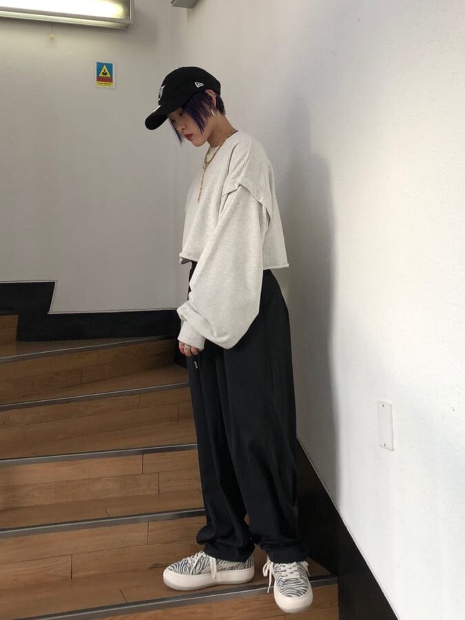 ブラック系のスラックス、グレー系のTシャツ/カットソー、ホワイト系のスニーカーを着用したレディースの冬コーディネートの2枚目の写真