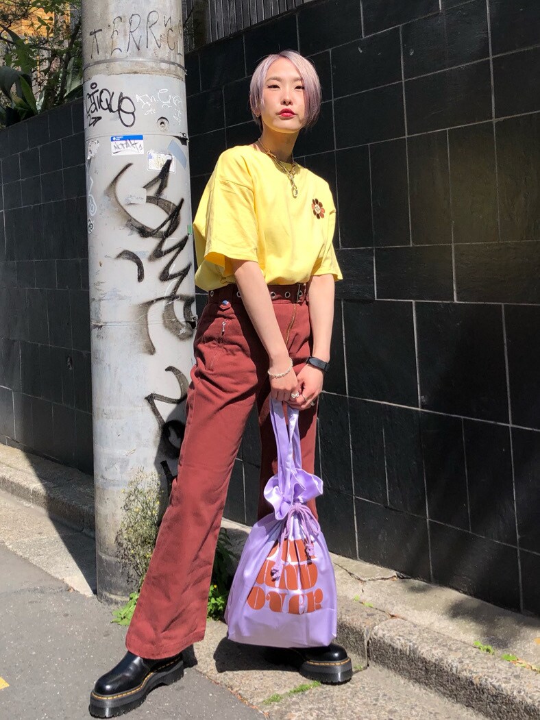 パープル系のトートバッグ、ブラウン系のデニムパンツ、イエロー系のTシャツ/カットソーを着用したレディースの春コーディネートの4枚目の写真