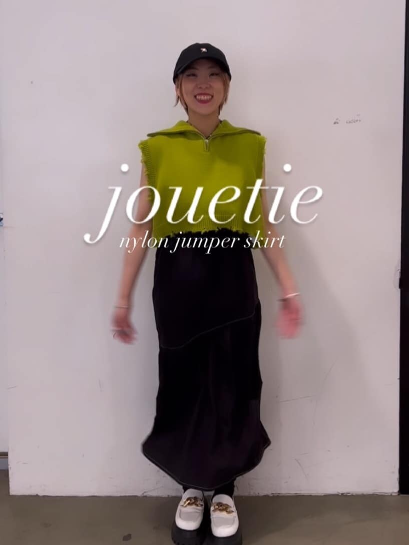 ホワイト系のローファー、グリーン系のベスト、ブラック系のジャンパースカートを着用したレディースの秋コーディネートの2枚目の写真