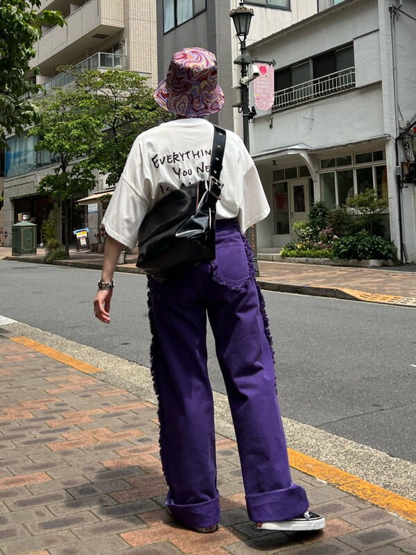 ブラック系のハンドバッグ、ホワイト系のTシャツ/カットソー、パープル系のデニムパンツを着用したレディースの夏コーディネートの3枚目の写真