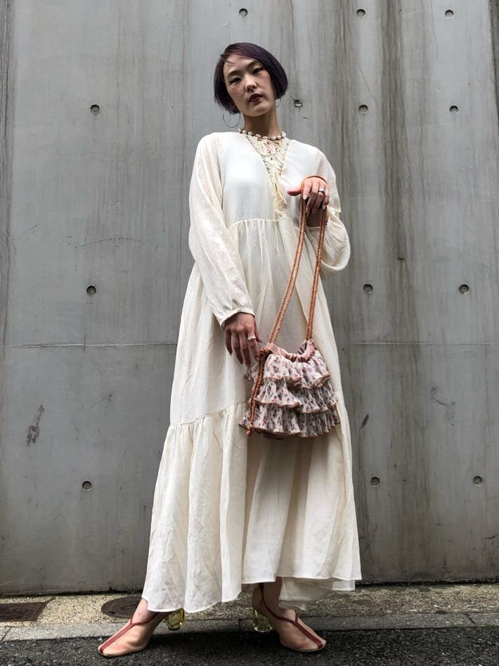 ホワイト系のワンピース、ホワイト系のパンプス、オレンジ系のハンドバッグを着用したレディースの夏コーディネートの3枚目の写真