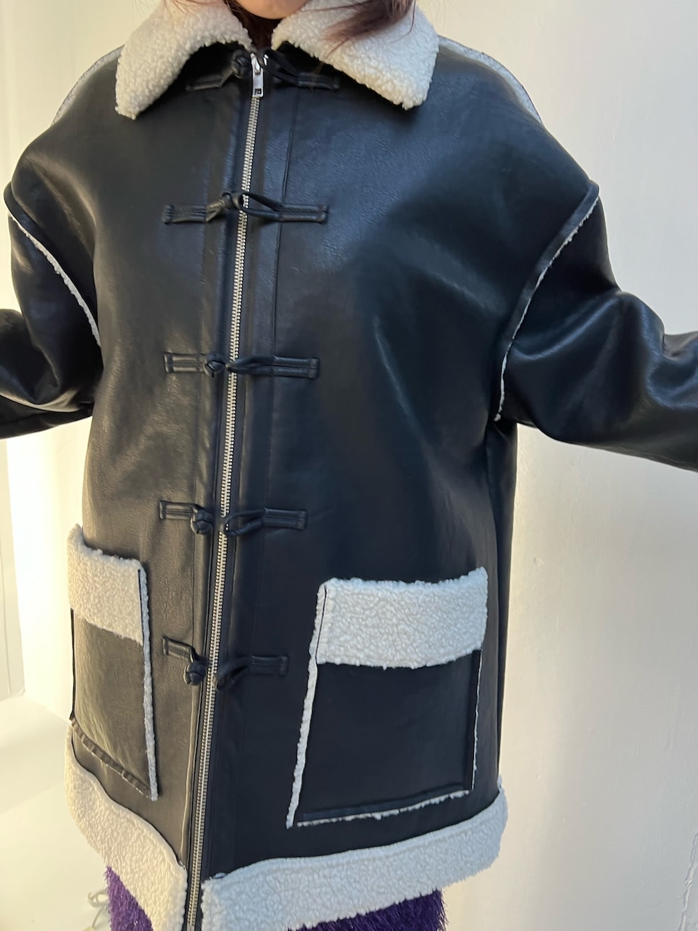 ブラック系のムートンコート、パープル系のスカート、ブラック系のスウェットを着用したレディースの夏コーディネートの8枚目の写真