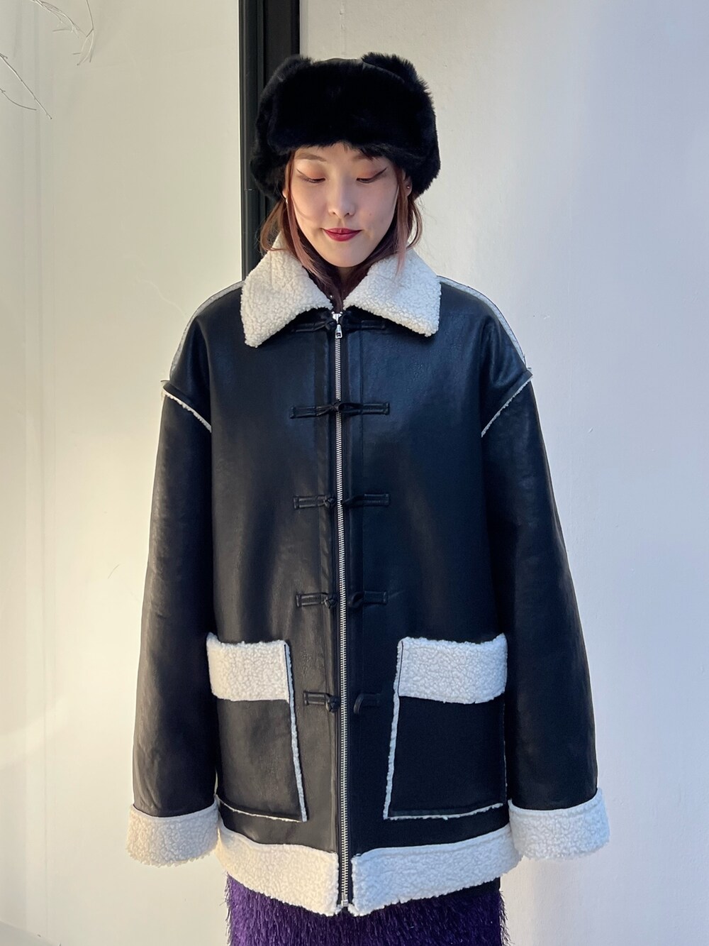 ブラック系のムートンコート、パープル系のスカート、ブラック系のスウェットを着用したレディースの夏コーディネートの6枚目の写真