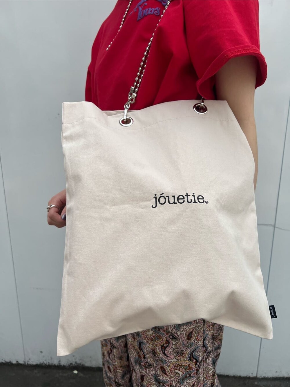 ホワイト系のトートバッグ、ブラック系のその他シューズ、レッド系のTシャツ/カットソーを着用したレディースの春コーディネートの9枚目の写真