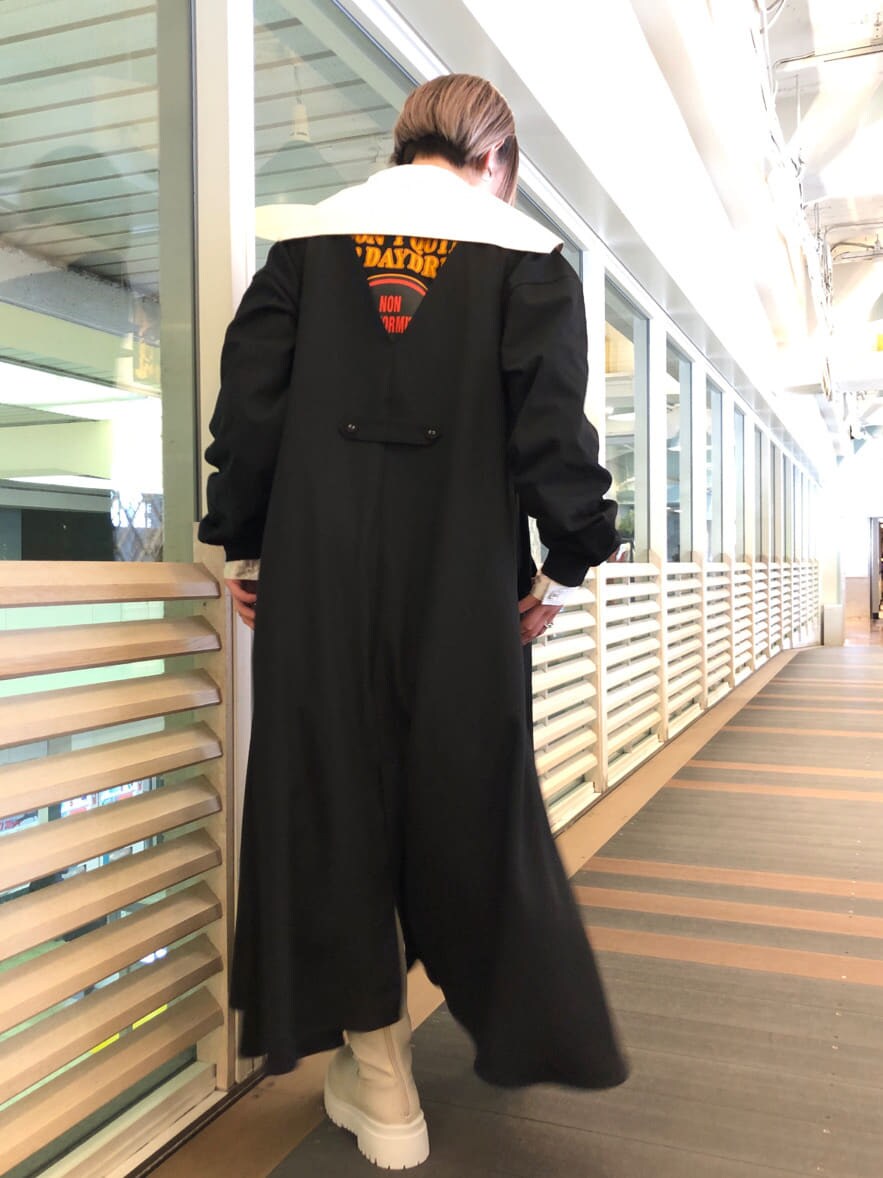 ホワイト系のシャツ/ブラウス、ブラック系のジャンパースカート、ホワイト系のブーツを着用したレディースの春コーディネートの3枚目の写真