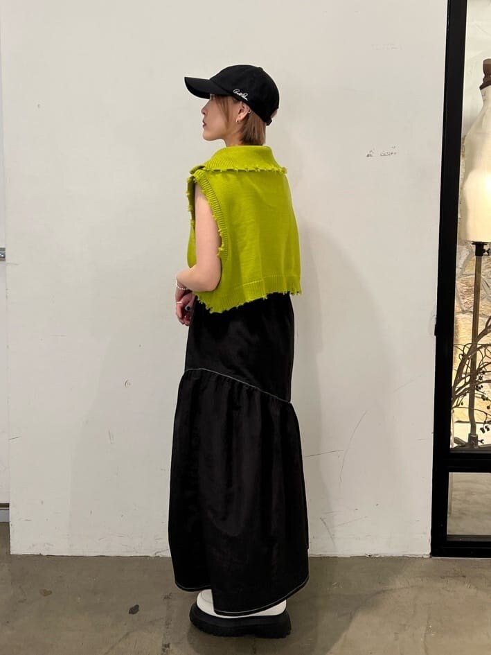 ホワイト系のローファー、グリーン系のベスト、ブラック系のジャンパースカートを着用したレディースの秋コーディネートの4枚目の写真