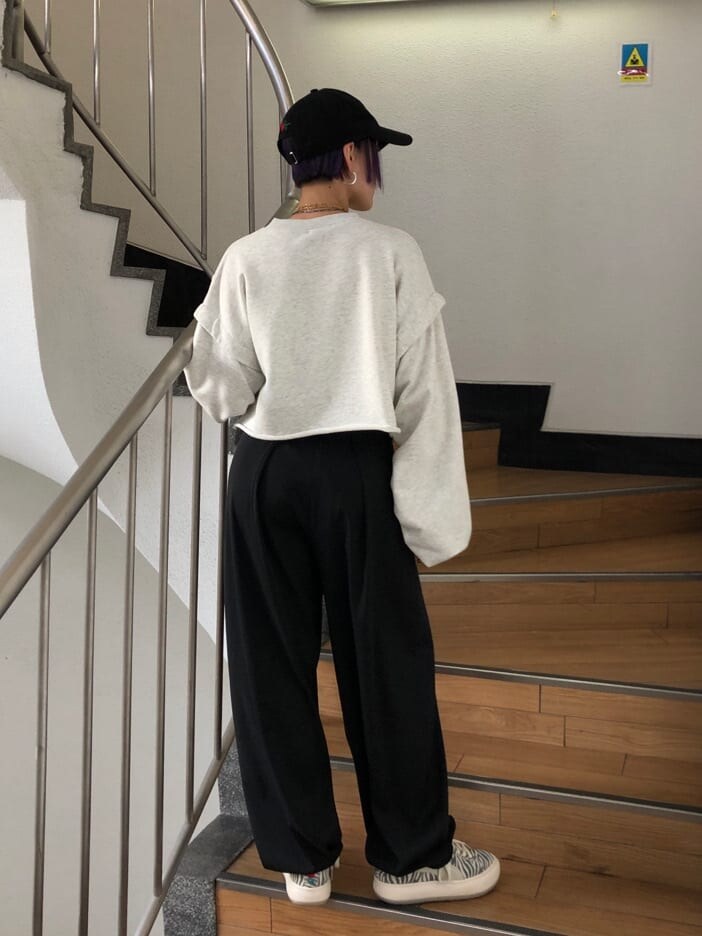 ブラック系のスラックス、グレー系のTシャツ/カットソー、ホワイト系のスニーカーを着用したレディースの冬コーディネートの3枚目の写真