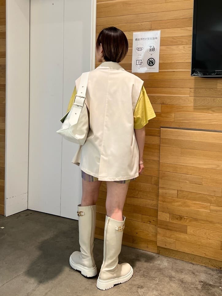 ホワイト系のブーツ、ホワイト系のベスト、ホワイト系のハンドバッグを着用したレディースの春コーディネートの3枚目の写真