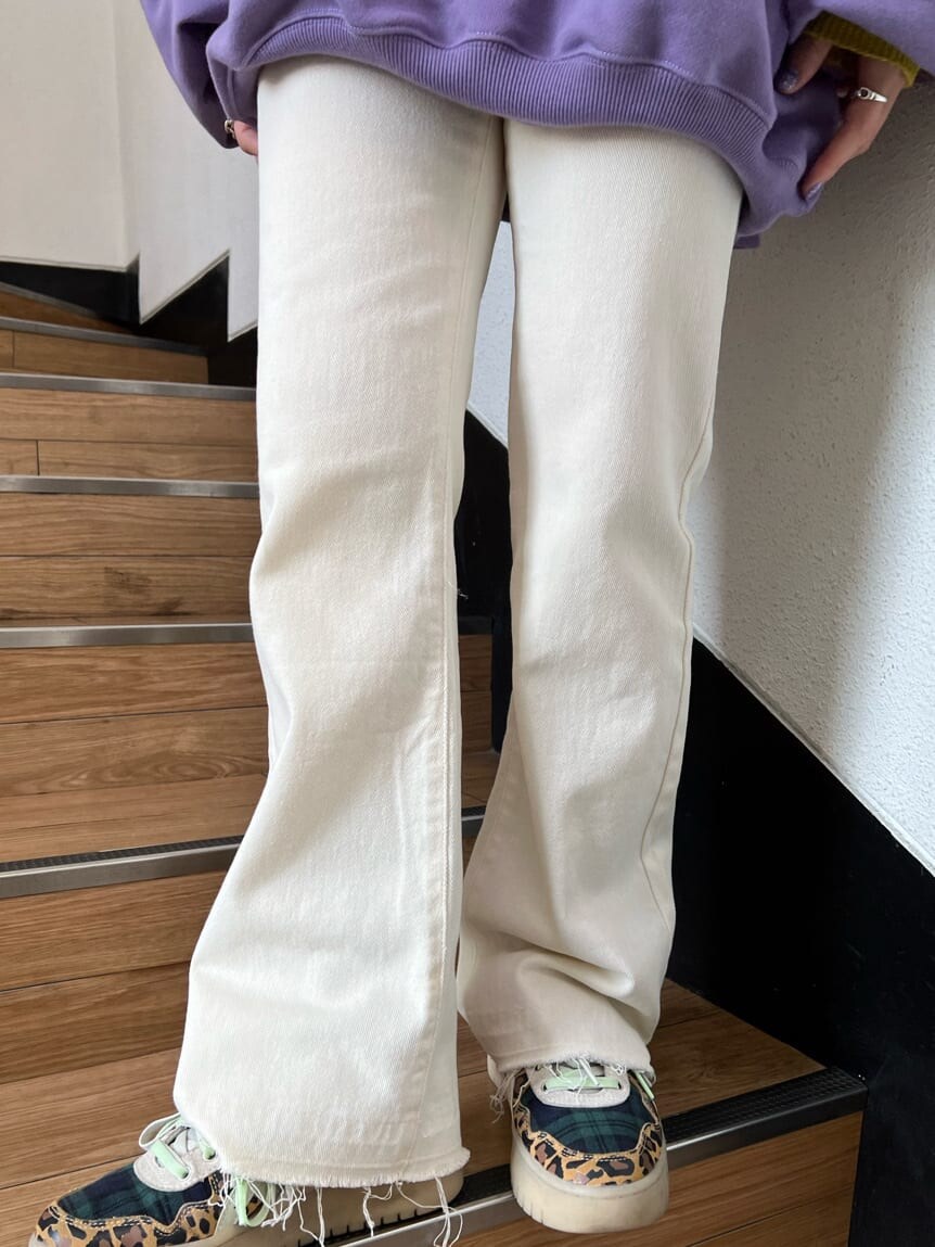 イエロー系のニット/セーター、パープル系のスウェット、ホワイト系のその他パンツを着用したレディースの秋コーディネートの9枚目の写真