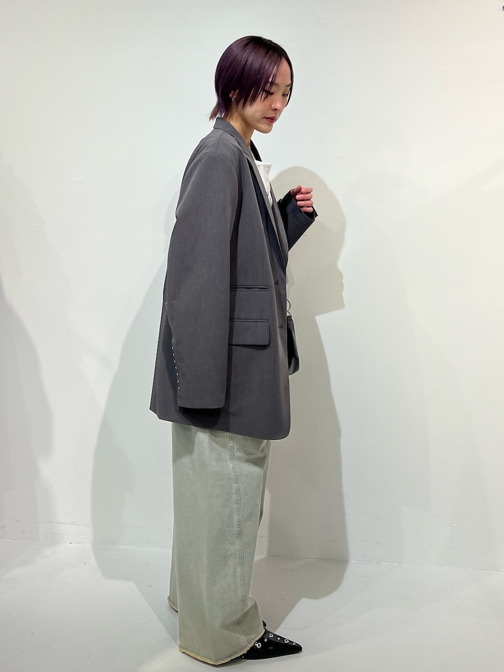 グレー系のテーラードジャケット、ブラック系のパンプス、ブルー系のデニムパンツを着用したレディースの春コーディネートの3枚目の写真