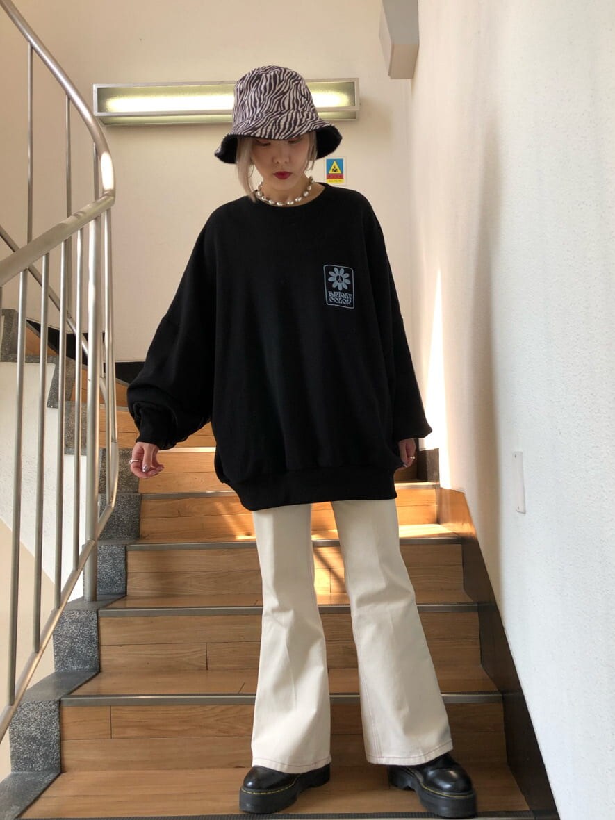 ホワイト系のデニムパンツ、ブラック系のスウェット、ブラック系のハットを着用したレディースの秋コーディネートの2枚目の写真