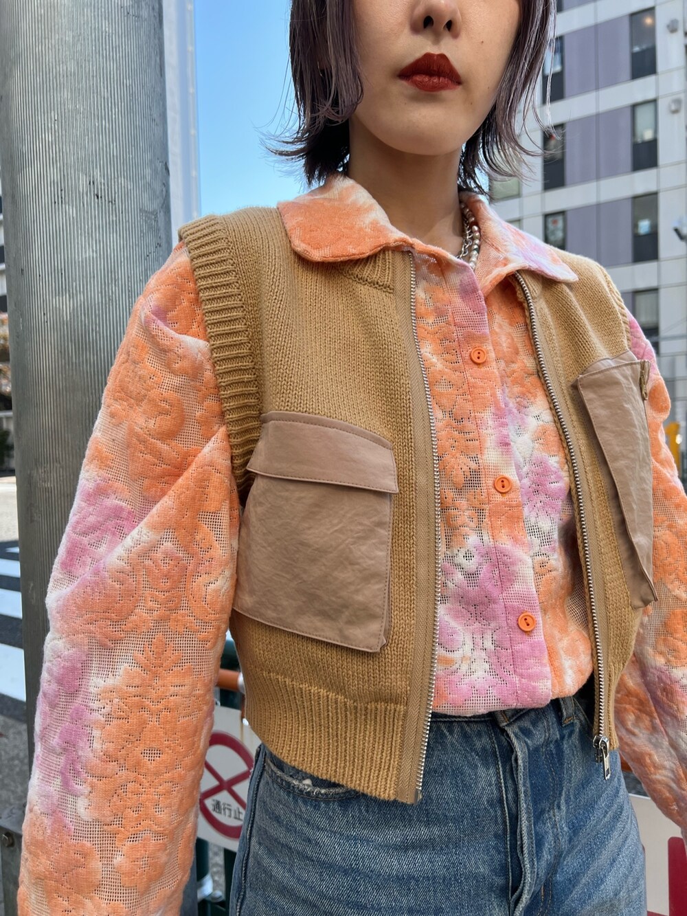 オレンジ系のシャツ/ブラウス、ベージュ系のベスト、ブルー系のデニムパンツを着用したレディースの春コーディネートの7枚目の写真