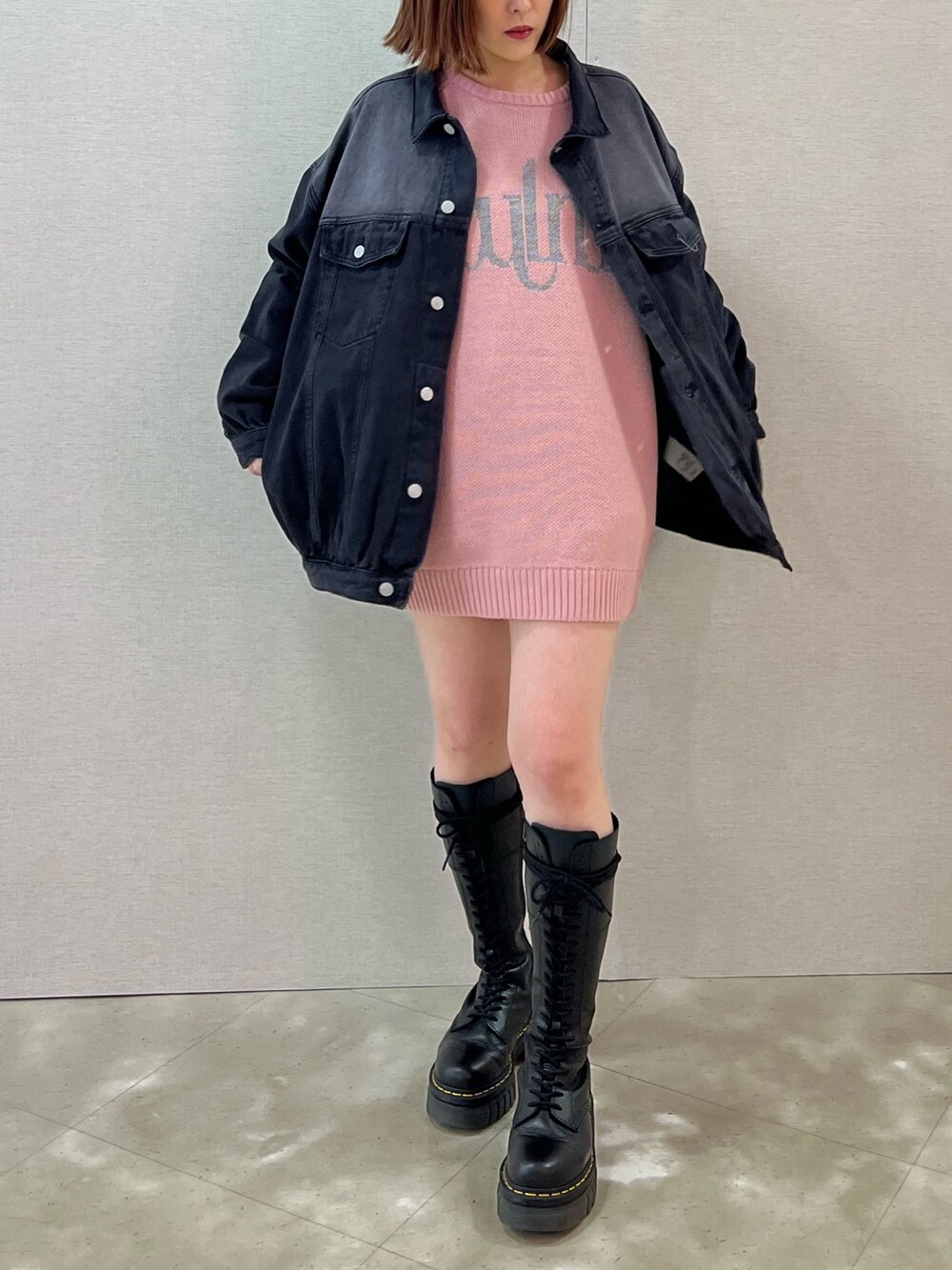 ホワイト系のニット/セーター、ブラック系のデニムジャケット、ブラック系のブーツを着用したレディースの春コーディネートの2枚目の写真