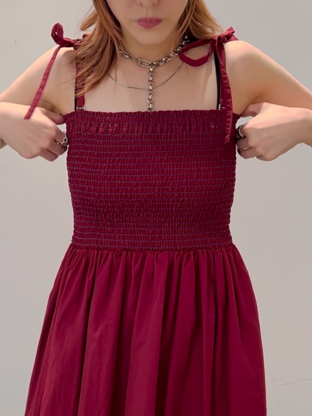 レッド系のワンピース、ホワイト系のショルダーバッグ、パープル系のスニーカーを着用したレディースの夏コーディネートの6枚目の写真