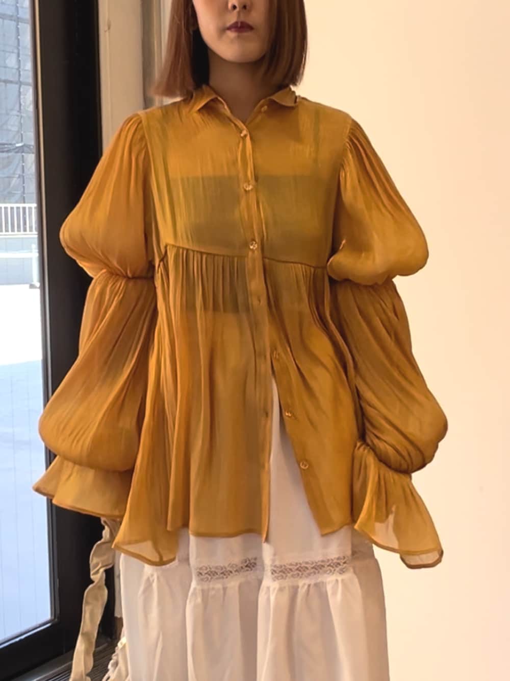 オレンジ系のシャツ/ブラウス、ホワイト系のスカート、ホワイト系のショルダーバッグを着用したレディースの春コーディネートの6枚目の写真