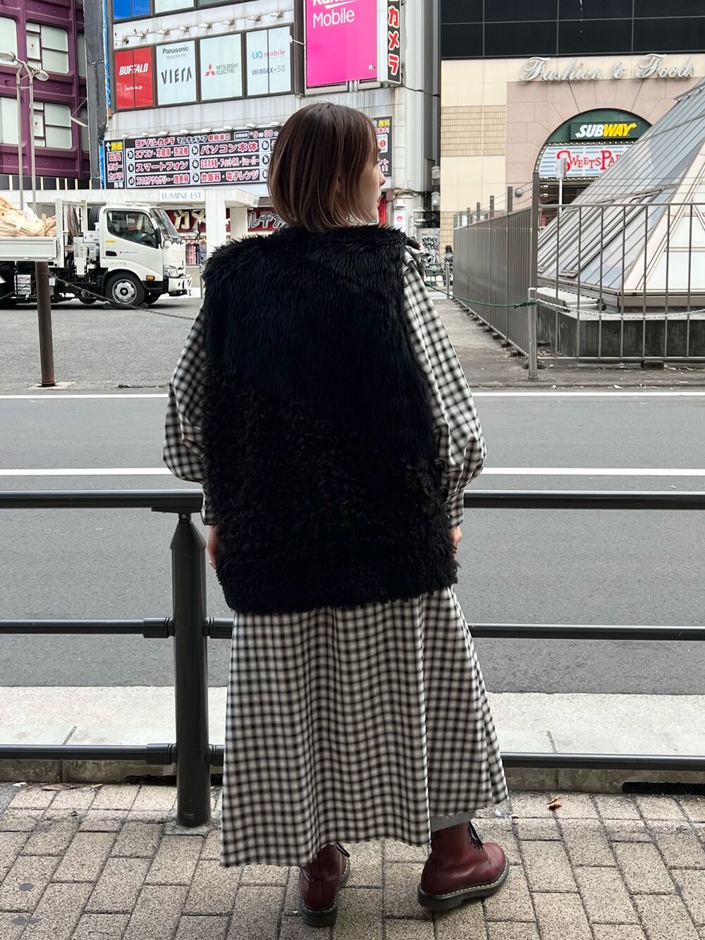 ブラック系のワンピース、ブラック系のベスト、ブルー系のデニムパンツを着用したレディースの冬コーディネートの4枚目の写真