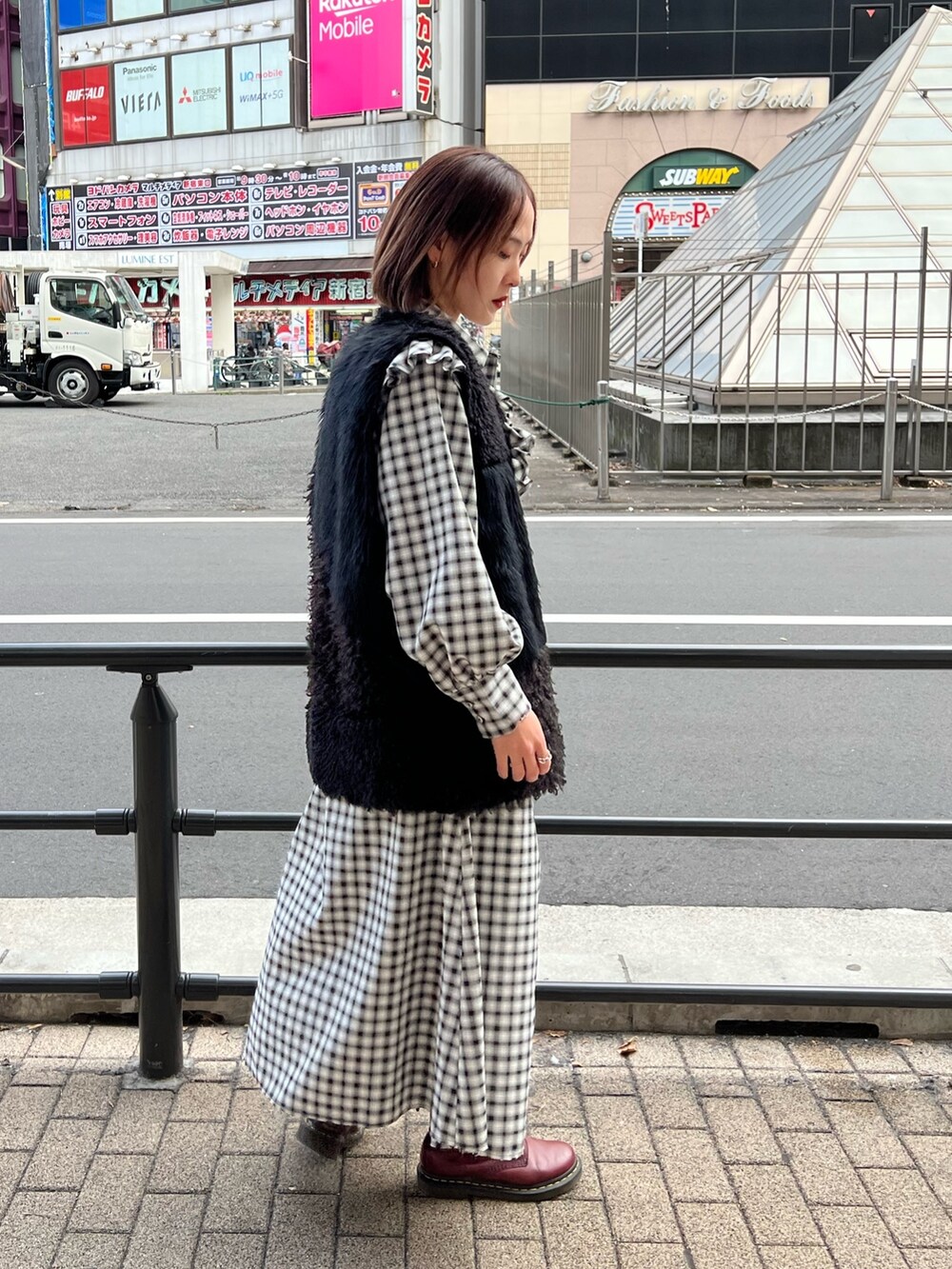 ブラック系のワンピース、ブラック系のベスト、ブルー系のデニムパンツを着用したレディースの冬コーディネートの5枚目の写真