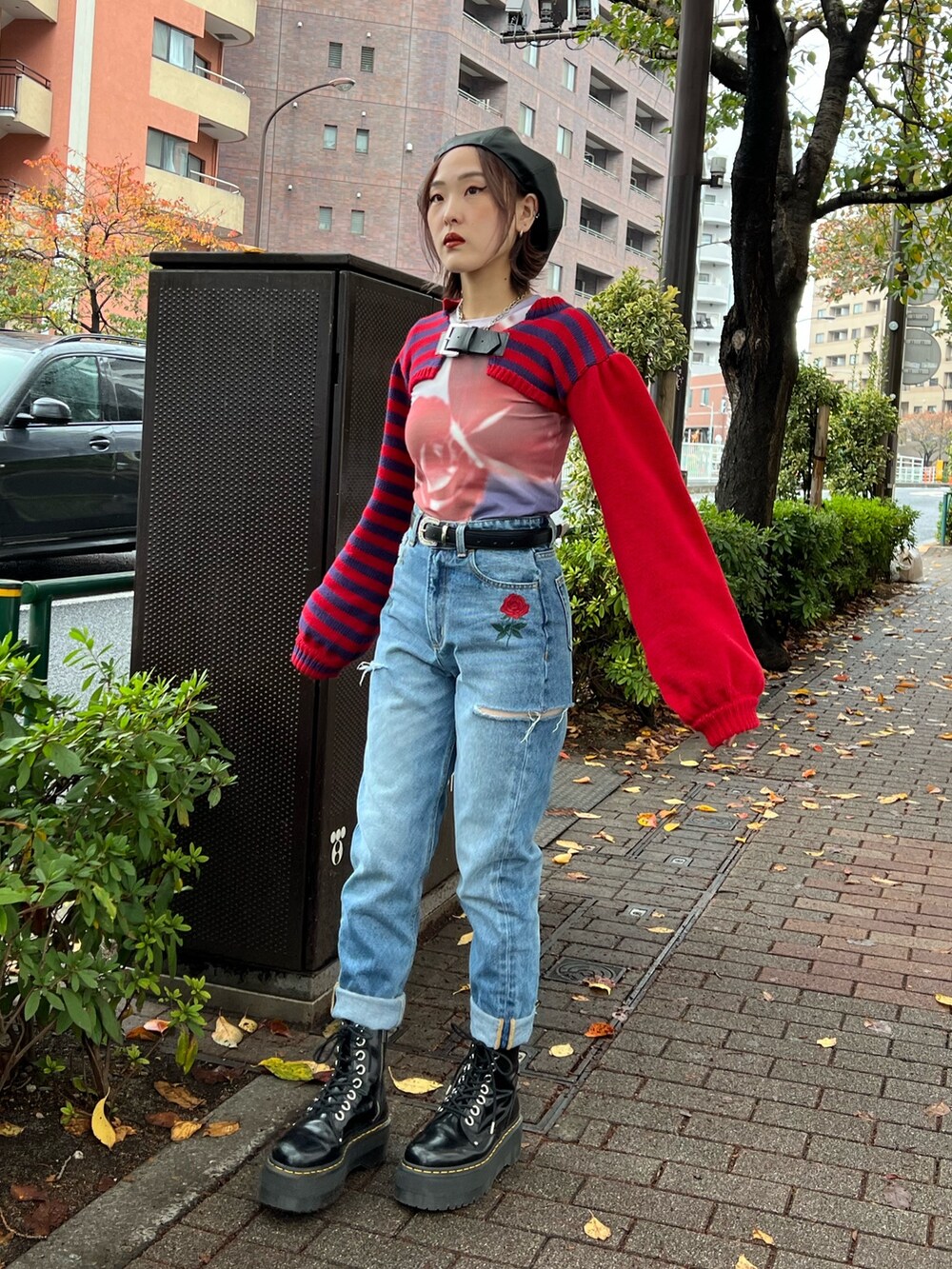 レッド系のニット/セーター、パープル系のTシャツ/カットソー、ブルー系のデニムパンツを着用したレディースの冬コーディネートの2枚目の写真