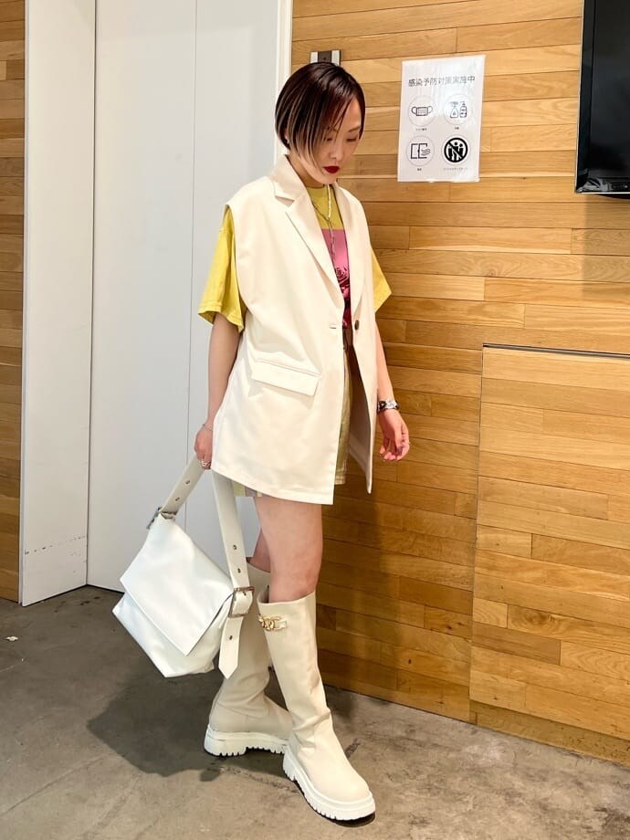 ホワイト系のブーツ、ホワイト系のベスト、ホワイト系のハンドバッグを着用したレディースの春コーディネートの2枚目の写真