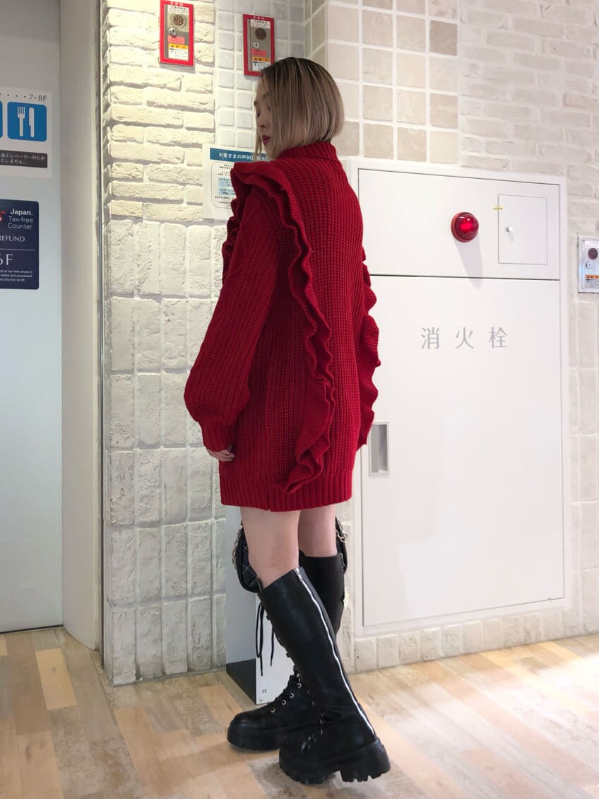 ブラック系のチェスターコート、レッド系のニット/セーター、ブラック系のブーツを着用したレディースの冬コーディネートの5枚目の写真