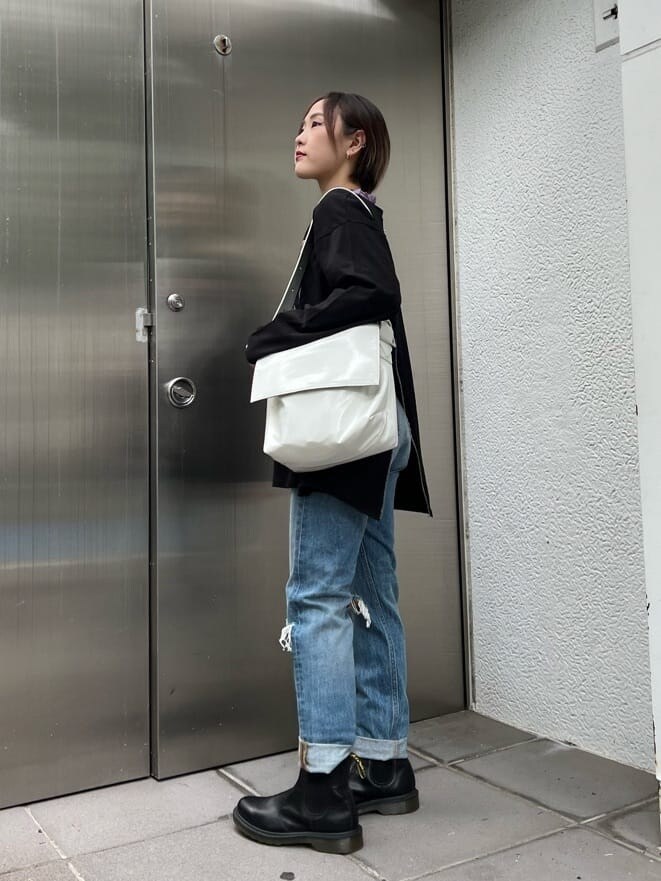 ブルー系のデニムパンツ、ホワイト系のハンドバッグ、パープル系のTシャツ/カットソーを着用したレディースの夏コーディネートの3枚目の写真