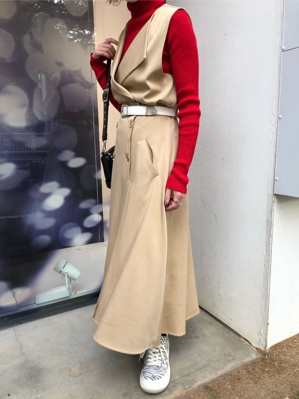 レッド系のニット/セーター、ホワイト系のスニーカー、ブラック系のショルダーバッグを着用したレディースの秋コーディネートの6枚目の写真