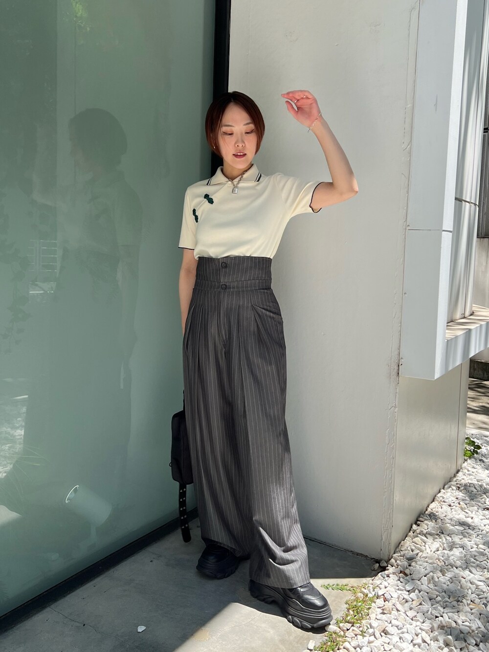 ホワイト系のポロシャツ、グレー系のスラックス、ブラック系のショルダーバッグを着用したレディースの夏コーディネートの5枚目の写真