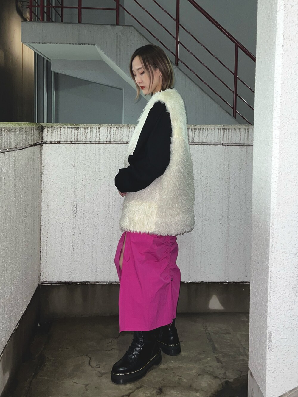 ブラック系のスウェット、ホワイト系のベスト、ピンク系のスカートを着用したレディースの冬コーディネートの4枚目の写真