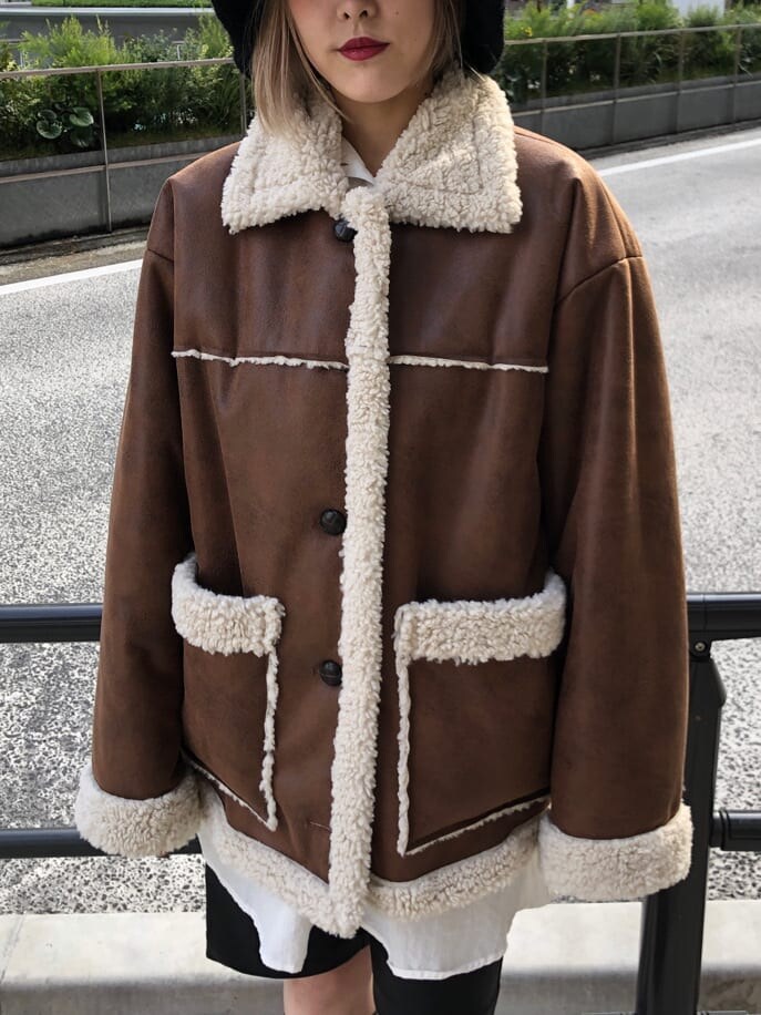 ブラウン系のムートンコート、ブラック系のシャツワンピース、ブラック系のハットを着用したレディースの秋コーディネートの8枚目の写真