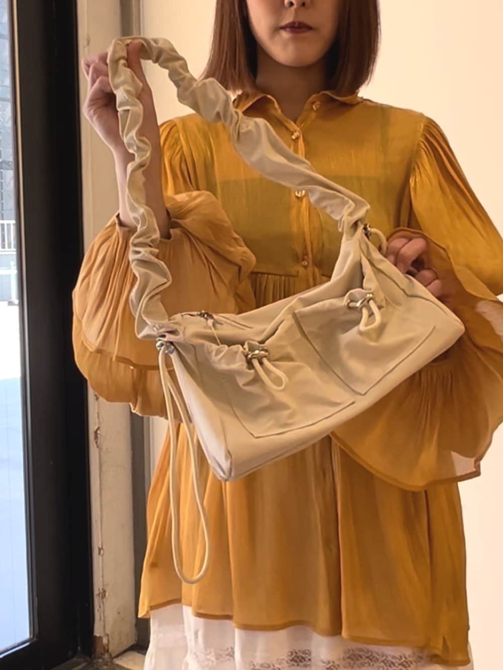 オレンジ系のシャツ/ブラウス、ホワイト系のスカート、ホワイト系のショルダーバッグを着用したレディースの春コーディネートの9枚目の写真