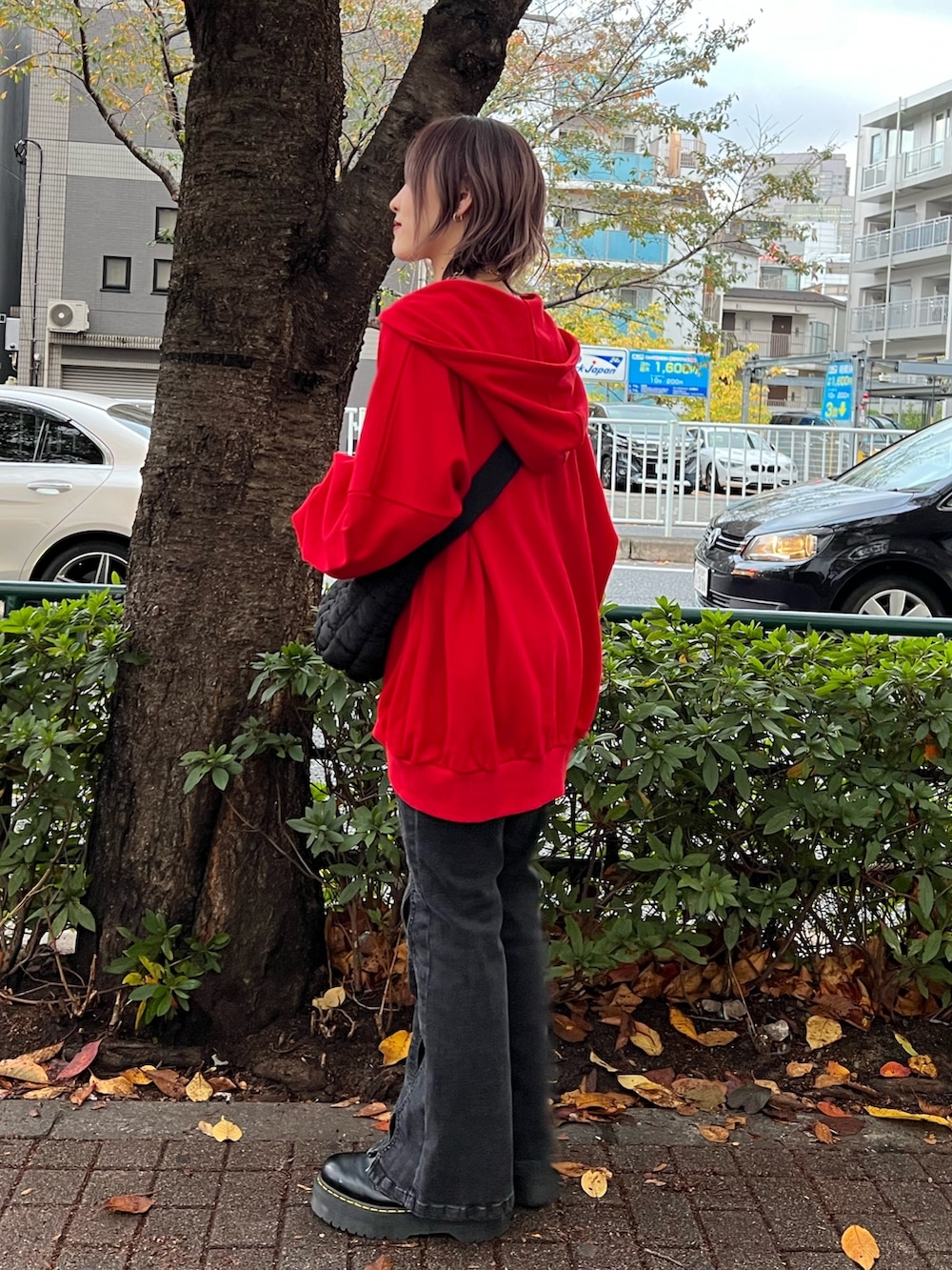 レッド系のパーカー、パープル系のTシャツ/カットソー、ブラック系のデニムパンツを着用したレディースの春コーディネートの2枚目の写真