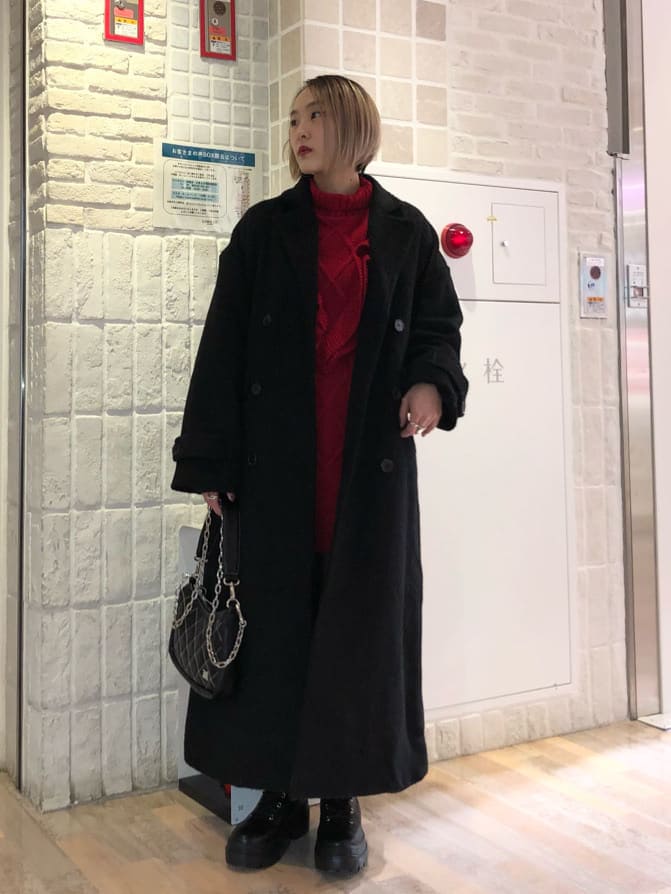 ブラック系のチェスターコート、レッド系のニット/セーター、ブラック系のブーツを着用したレディースの冬コーディネートの2枚目の写真