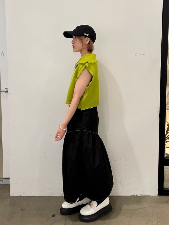 ホワイト系のローファー、グリーン系のベスト、ブラック系のジャンパースカートを着用したレディースの秋コーディネートの3枚目の写真