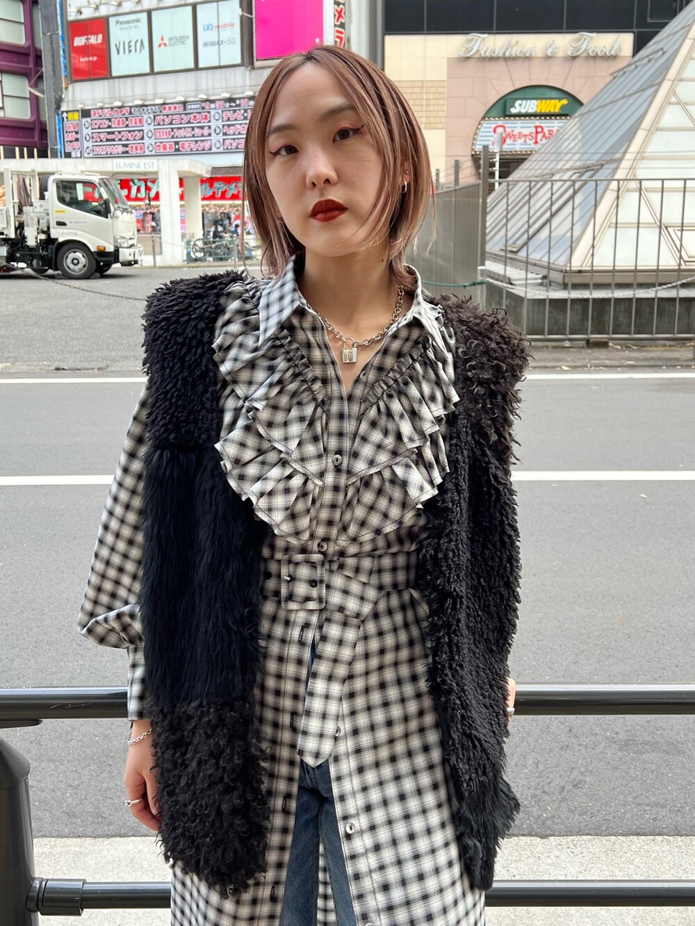 ブラック系のワンピース、ブラック系のベスト、ブルー系のデニムパンツを着用したレディースの冬コーディネートの6枚目の写真