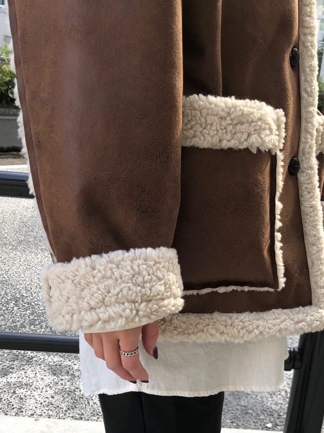 ブラウン系のムートンコート、ブラック系のシャツワンピース、ブラック系のハットを着用したレディースの秋コーディネートの9枚目の写真