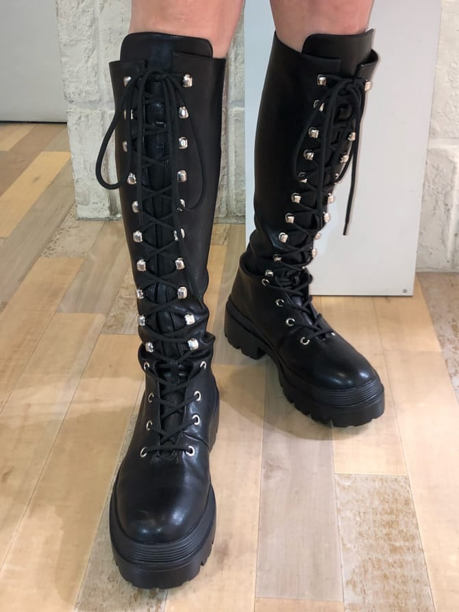 ブラック系のチェスターコート、レッド系のニット/セーター、ブラック系のブーツを着用したレディースの冬コーディネートの10枚目の写真