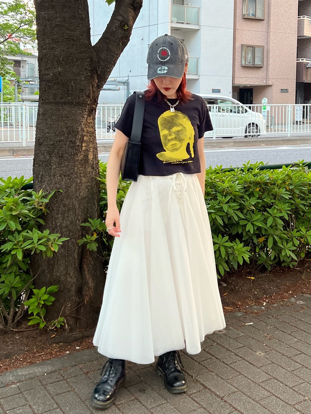 ブラック系のTシャツ/カットソー、ホワイト系のスカート、ブラック系のハンドバッグを着用したレディースの夏コーディネートの4枚目の写真