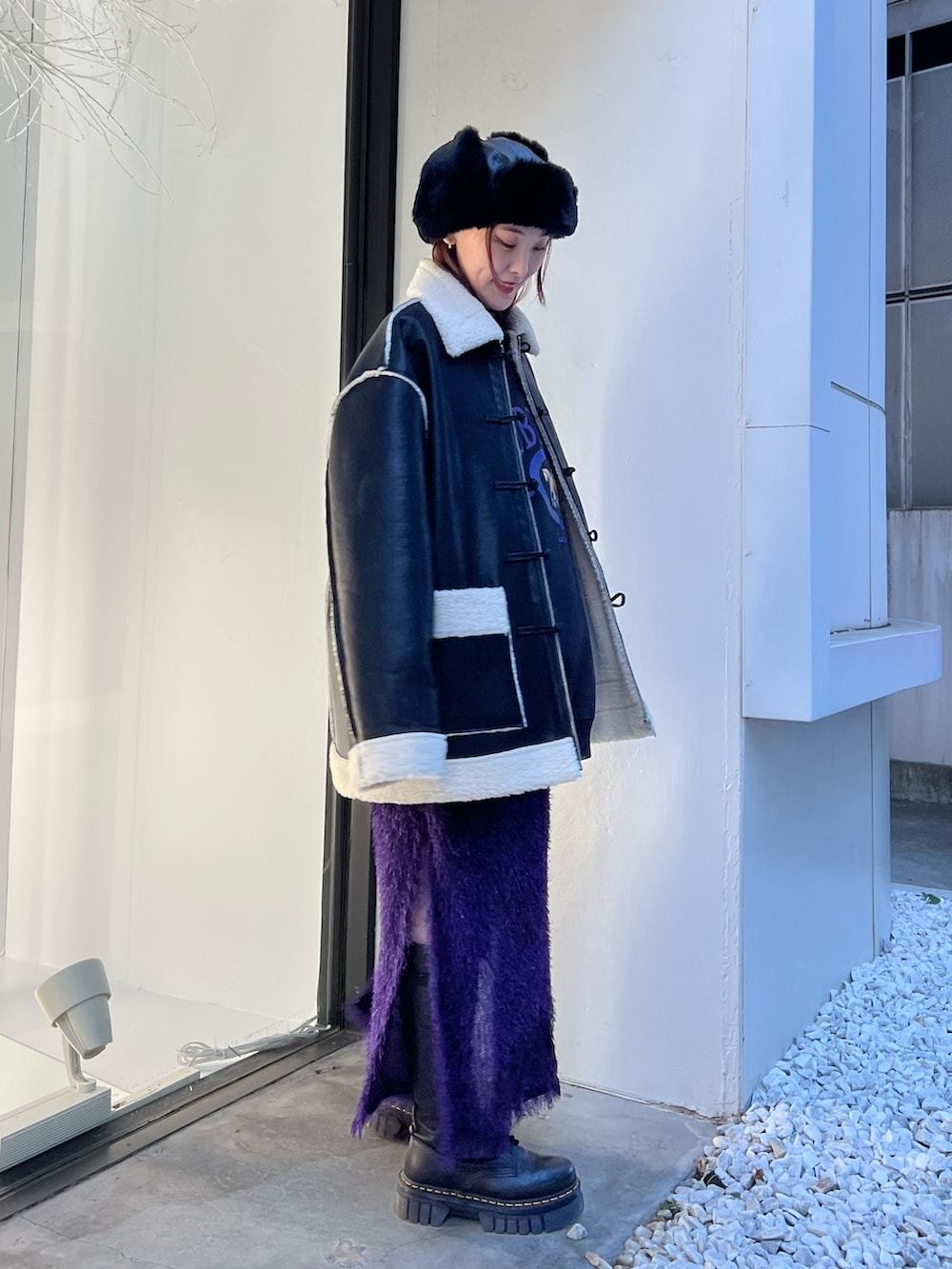 ブラック系のムートンコート、パープル系のスカート、ブラック系のスウェットを着用したレディースの夏コーディネートの2枚目の写真