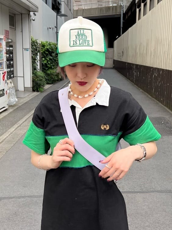ブラック系のワンピース、パープル系のハンドバッグ、グリーン系のキャップを着用したレディースの夏コーディネートの6枚目の写真