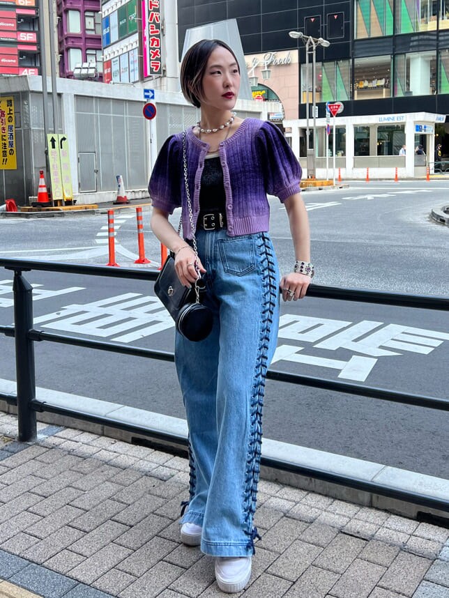 ブラック系のハンドバッグ、ブラック系のニット/セーター、ブルー系のデニムパンツを着用したレディースの夏コーディネートの4枚目の写真