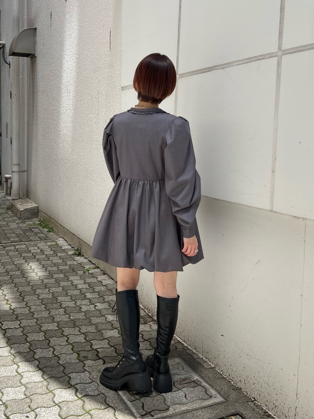 グレー系のワンピース、ブラック系のブーツを着用したレディースの夏コーディネートの2枚目の写真