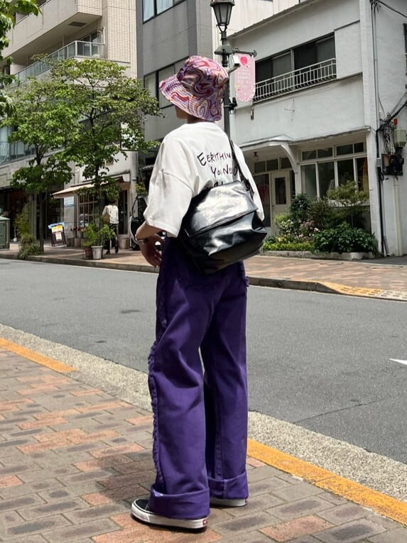 ブラック系のハンドバッグ、ホワイト系のTシャツ/カットソー、パープル系のデニムパンツを着用したレディースの夏コーディネートの2枚目の写真